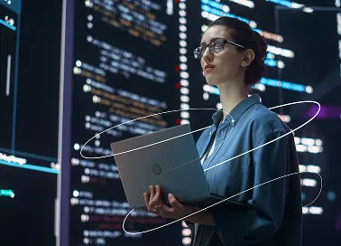 A woman in an office attire holding a laptop.