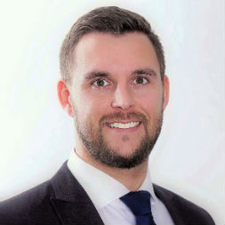 Portrait of a smiling man in a suit with a dark tie.