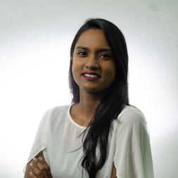 Person smiling in front of a white background wearing a white shirt.
