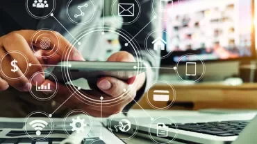 Person using smartphone with digital icons overlaying a laptop and desk.