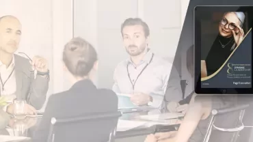 Business meeting with four people and a digital tablet displaying a leadership book cover.