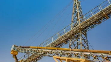 Industrial structure with yellow beams and clear blue sky.