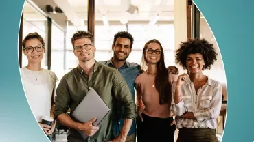 Group of five smiling professionals in an office