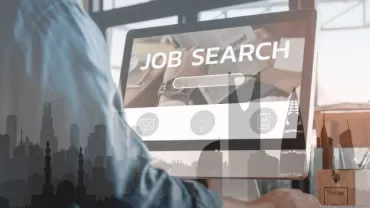 Person using a computer for job searching, city skyline overlay.