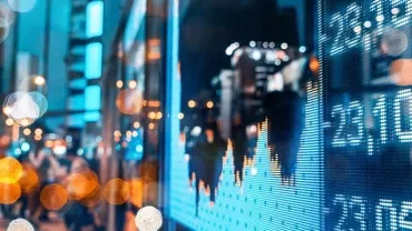 Blurred city street scene with electronic stock market display.