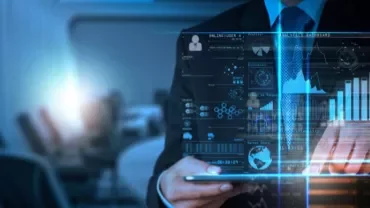 Person using a tablet with digital data and graphs on a virtual screen.