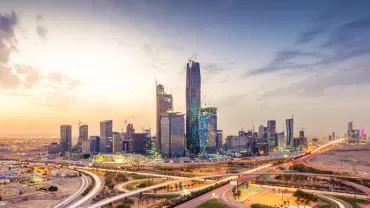 Modern skyline of Riyadh with skyscrapers and a colorful sunset.
