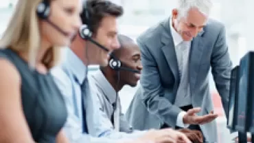 Team of customer service agents working at computers, all wearing headsets.