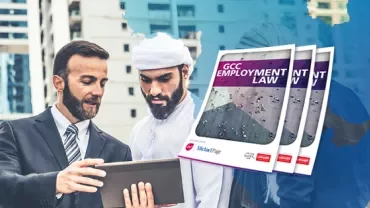 Two men discussing GCC Employment Law booklets outdoors.