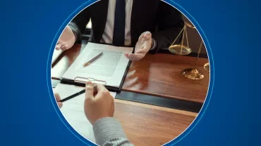 Two people at a table with legal documents and a scale of justice.