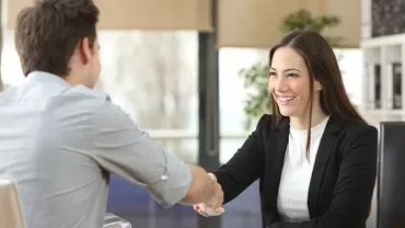 Business people shaking hands in an office setting.