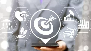 Businessman holding a phone with icons of various industries and a target symbol overlayed.