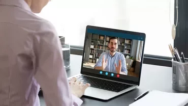 Person attending a video call on a laptop at a desk.