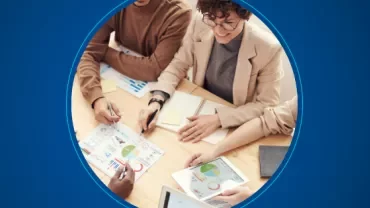 Group of people reviewing charts at a table in a meeting.