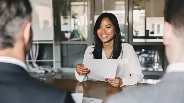 Woman smiling during a meeting, holding a paper.