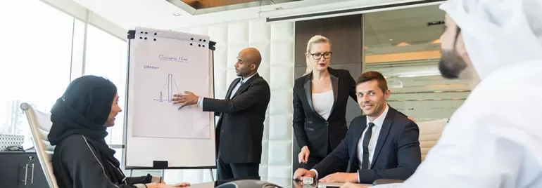 Business meeting with diverse team discussing a presentation on a flipchart.