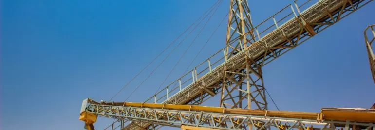 Industrial structure with yellow beams and clear blue sky.