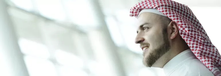 Man wearing a red and white keffiyeh in a bright room.