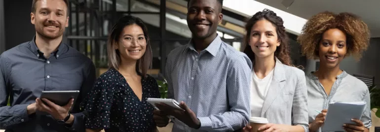 Five people standing in an office, smiling and holding various items.