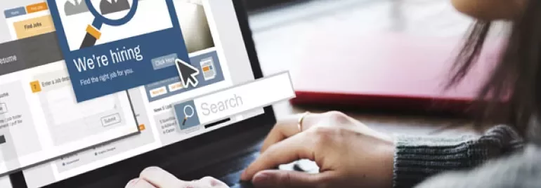Person using a laptop with a 'We're hiring' pop-up on screen.