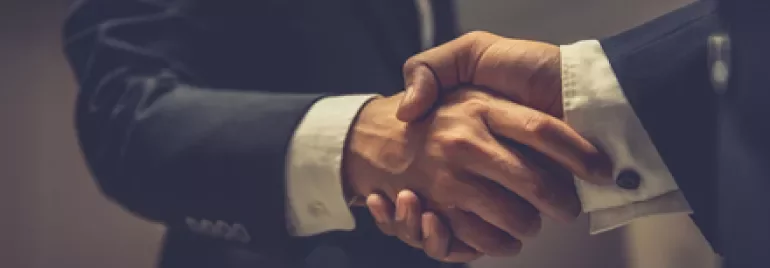 Two business professionals shaking hands in an office setting.