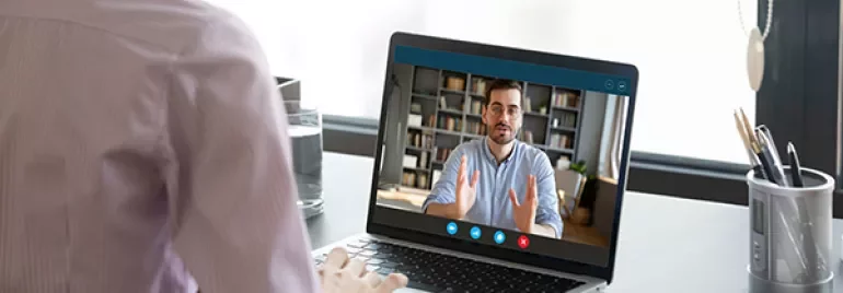 Person attending a video call on a laptop at a desk.