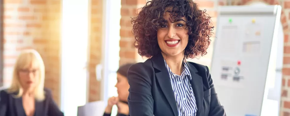 Smiling person with curly hair in office setting.