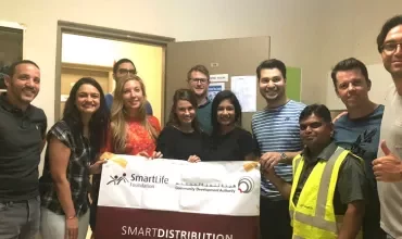 Group of people holding a SmartLife Foundation banner in a room.