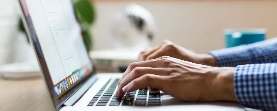Person typing on a laptop with a blurred background.