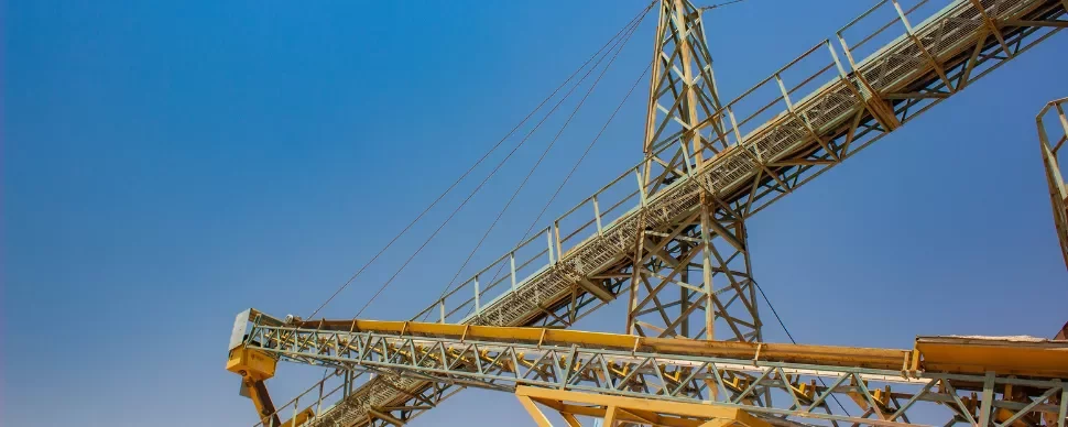 Industrial structure with yellow beams and clear blue sky.