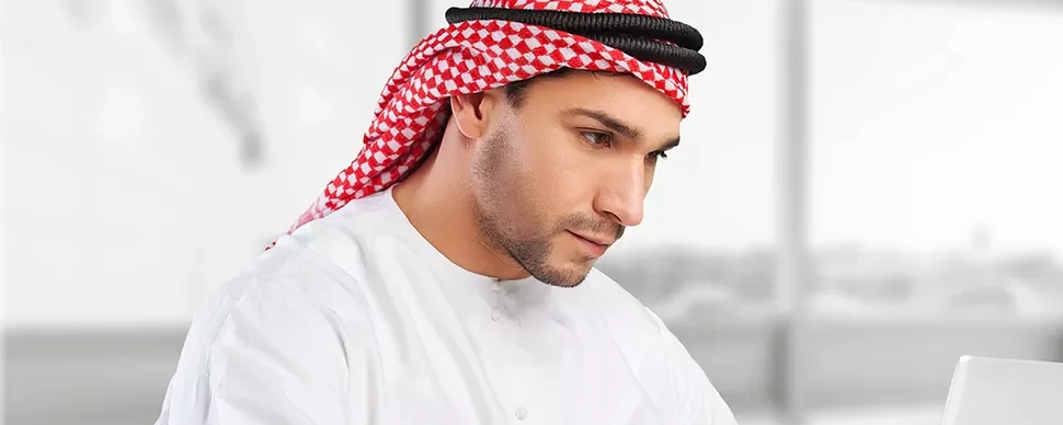 Man in traditional attire working on a laptop.