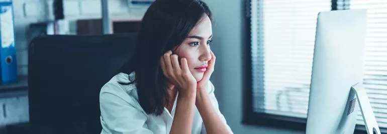 Woman sitting at a desk, staring intently at a computer screen.