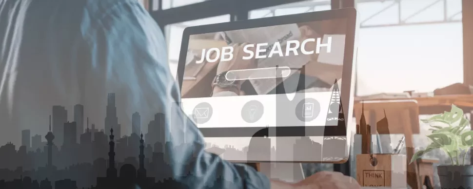 Person using a computer for job searching, city skyline overlay.