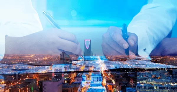 Two individuals writing with pens over a cityscape background.