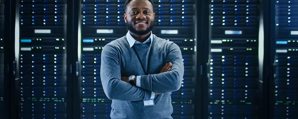 Smiling man standing in front of server racks in a data center.
