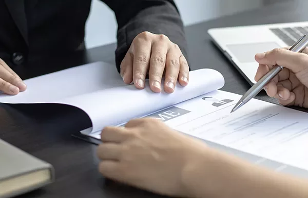 Two people reviewing a resume at a desk with a laptop.