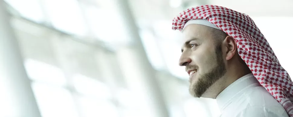 Man wearing a red and white keffiyeh in a bright room.