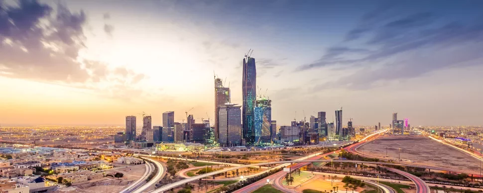 Modern skyline of Riyadh with skyscrapers and a colorful sunset.