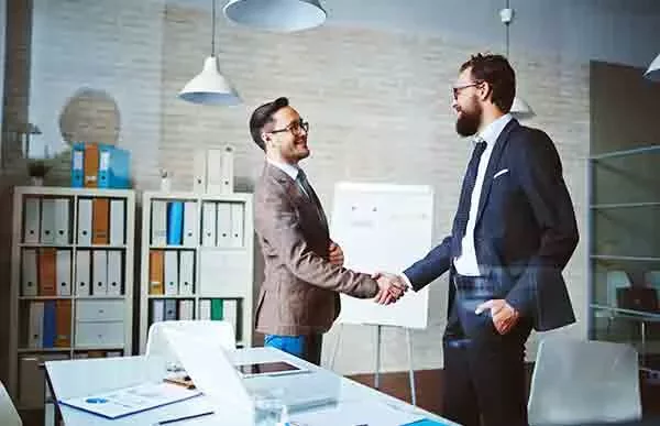 Two businessmen shaking hands in a modern office.