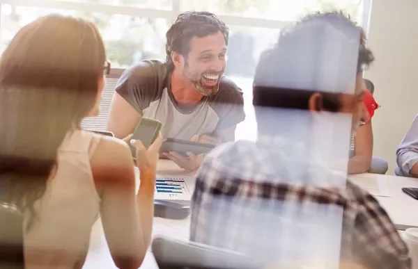 Group of people laughing and working together in a modern office.