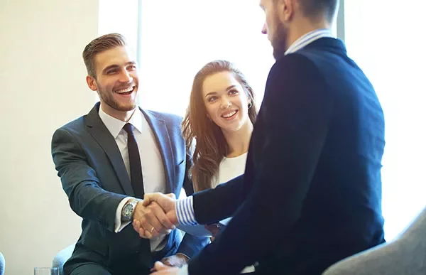Smiling professionals shaking hands in an office setting.