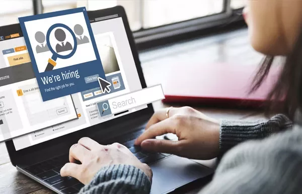 Person using a laptop with a 'We're hiring' pop-up on screen.