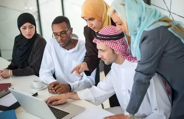 Group of professionals in discussion, focused on a laptop screen.