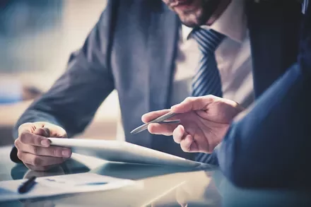 Two people in suits reviewing a document at a desk.