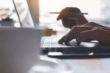 Close-up of hands typing on a laptop keyboard.
