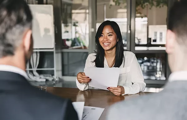 Woman smiling during a meeting, holding a paper.