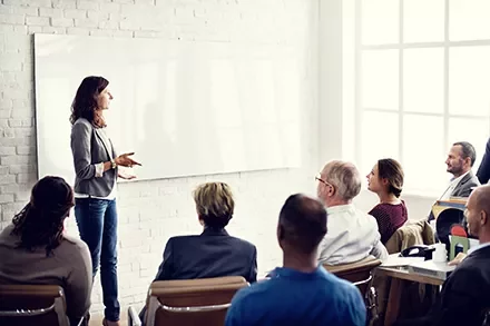 Person giving a presentation to a group in a bright room.